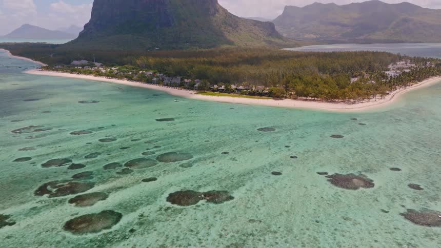 An aerial tilt-up reveals the stunning Le Morne Brabant mountain, its sandy peninsula, and the surrounding turquoise ocean in Mauritius