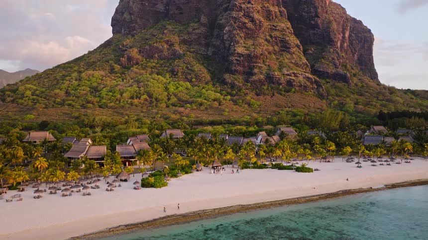 A stunning aerial pull-back shot reveals a beach wedding at a luxury resort nestled at the foot of the iconic Le Morne mountain in Mauritius