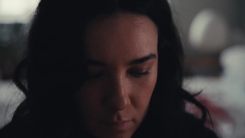 A somber close-up of a woman's face as she looks down in deep contemplation