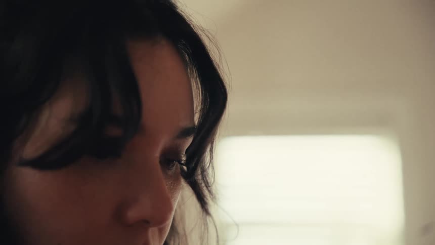 An intimate close-up shot of a thoughtful young woman's face as she looks down pensively