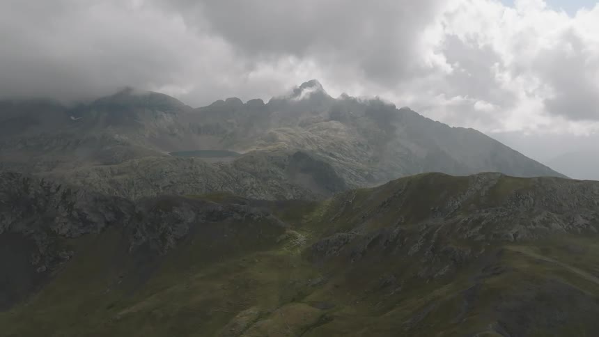 A stunning aerial view of a rugged mountain range shrouded in moody, dramatic clouds