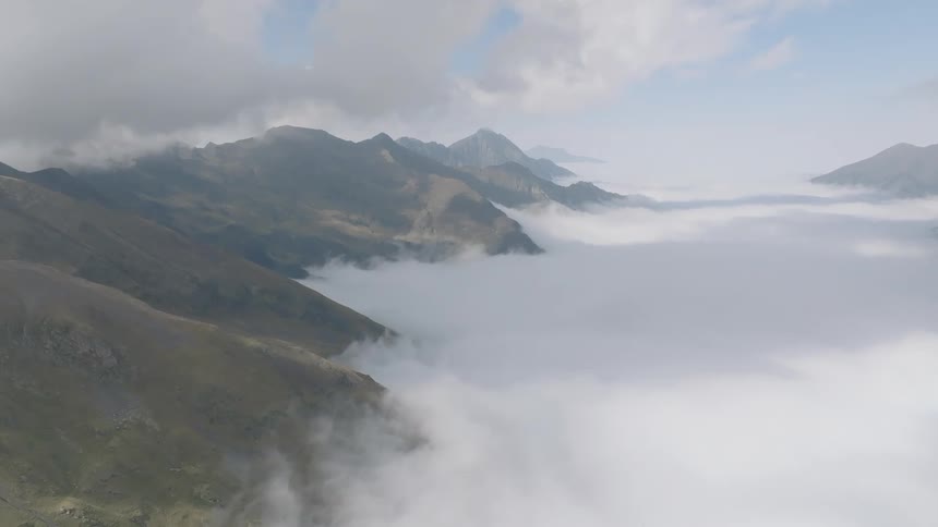 An awe-inspiring aerial view shows majestic mountain peaks rising above a thick sea of clouds filling the valley below