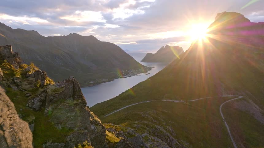 An awe-inspiring aerial view reveals a stunning Norwegian fjord and coastal village as the sun sets over the mountains