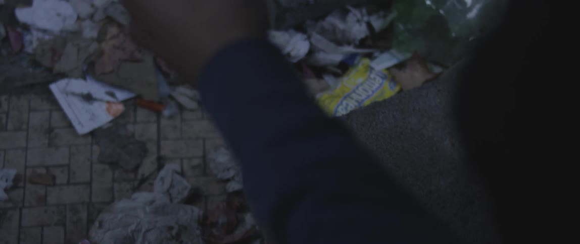 Black man picks up a syringe off the ground