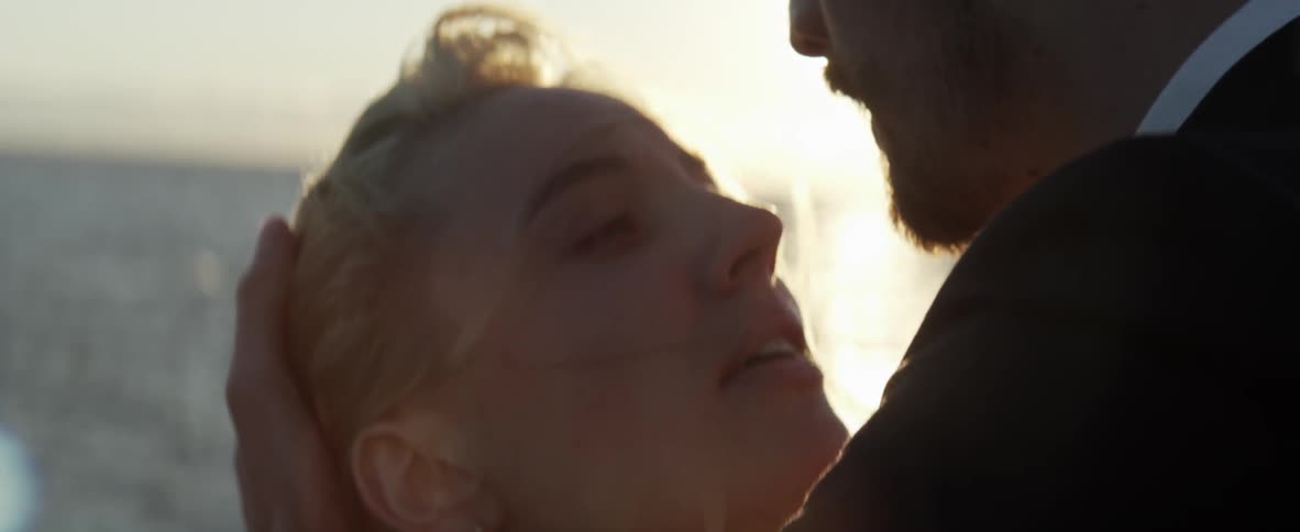 A woman looks up at a man as he smooths her hair back
