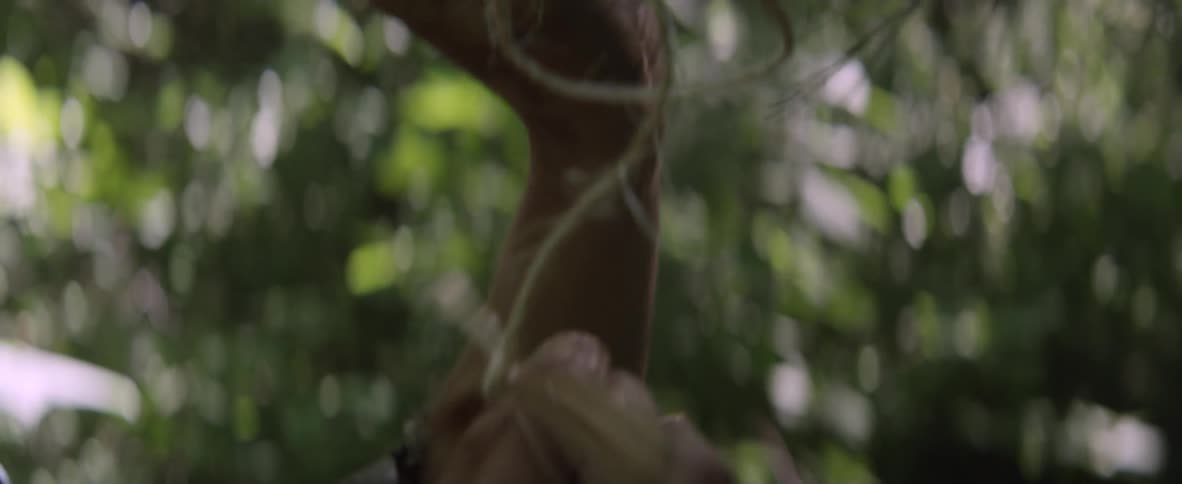 A woman in a mask ties a string on a pine tree branch