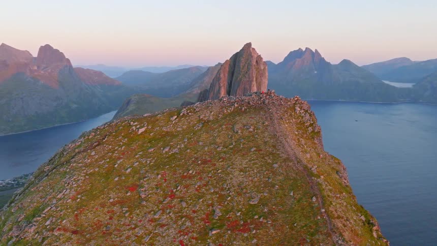 A breathtaking aerial flight over the Hesten mountain ridge in Senja, Norway reveals the iconic Segla peak and surrounding fjords at sunset