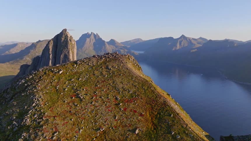 A majestic aerial pullback reveals the spectacular Segla mountain peak and surrounding fjords on Norway's Senja island at sunset