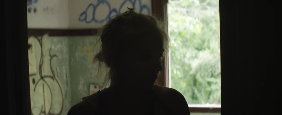 A woman stands in a room with the walls covered in graffiti