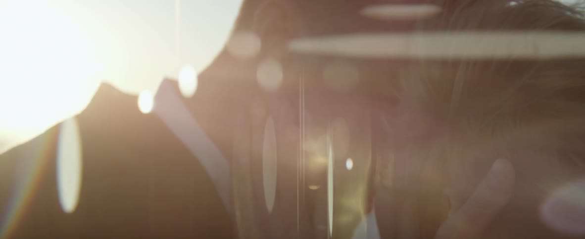 A man and woman kiss with the sun shining down brightly on them