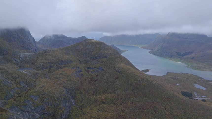 An epic aerial view captures a vast fjord nestled between rugged mountains under a cloudy sky in Norway