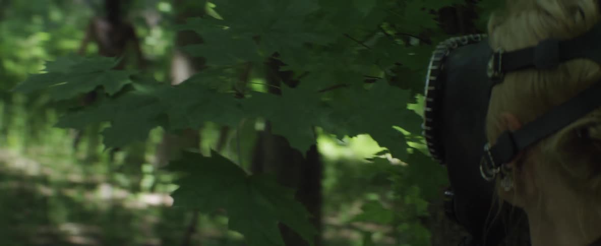 A man with face paint walks through the forest