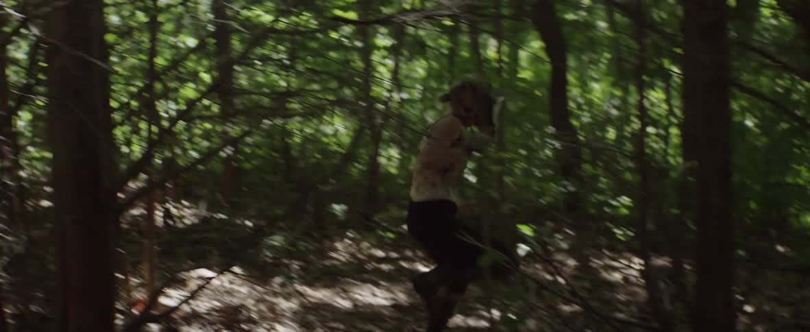 Woman wearing full face mask being chased by man in forest