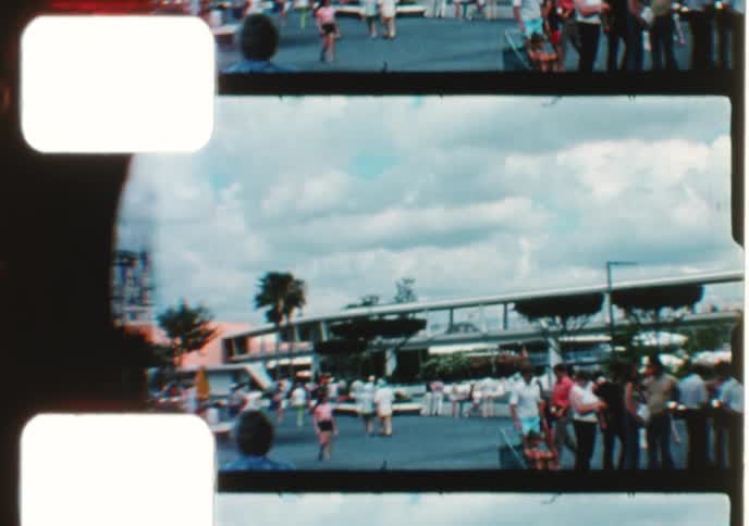 Vintage 8mm footage captures nostalgic scenes of a bustling theme park and a mother and son posing for the camera