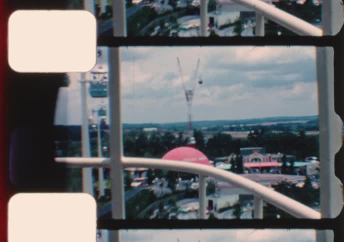 Vintage 8mm film provides an aerial tour of a bustling theme park, showcasing classic rides and architecture from a high vantage point