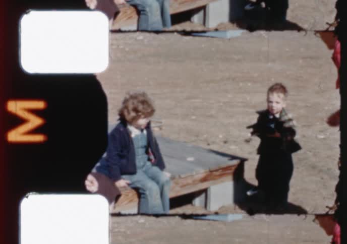 A vintage home movie captures children playing with their family and pet collie dog outdoors on a sunny day
