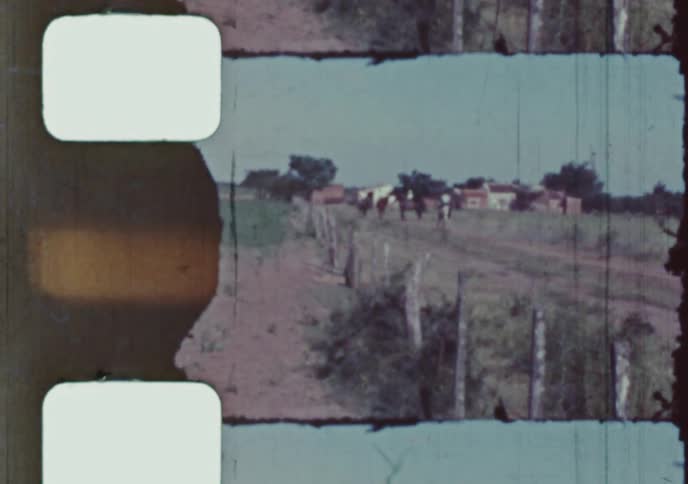 A damaged vintage film captures a man riding a horse down a country road as two boys walk alongside