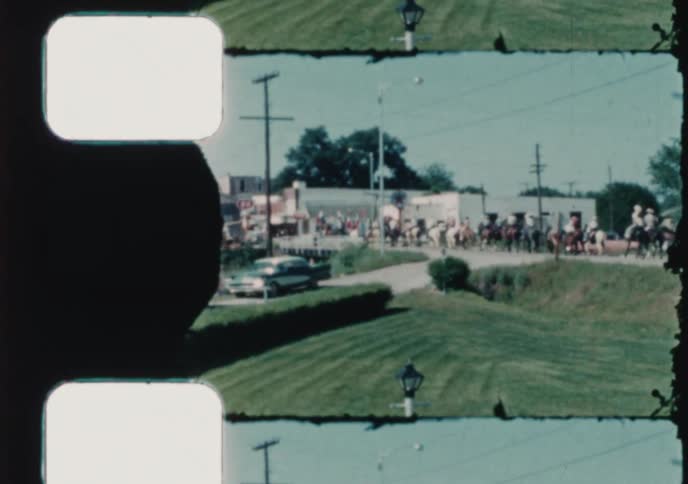 Vintage 16mm film captures scenes from a small town parade with horseback riders and a display of cattle