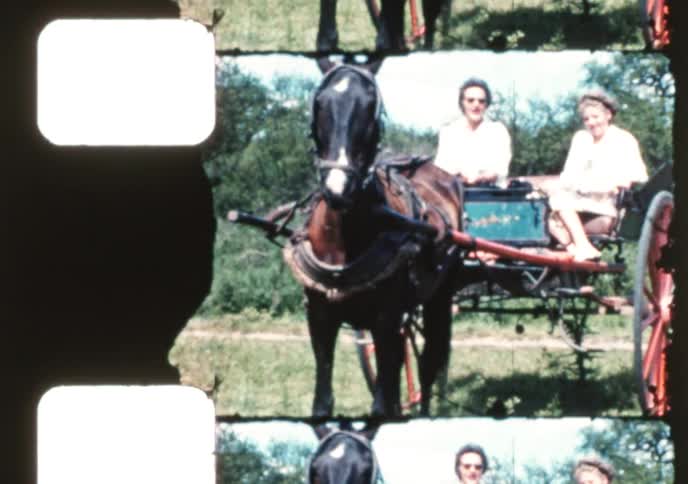 Vintage home movie captures two women smiling and waving from a horse-drawn cart on a sunny day in the country