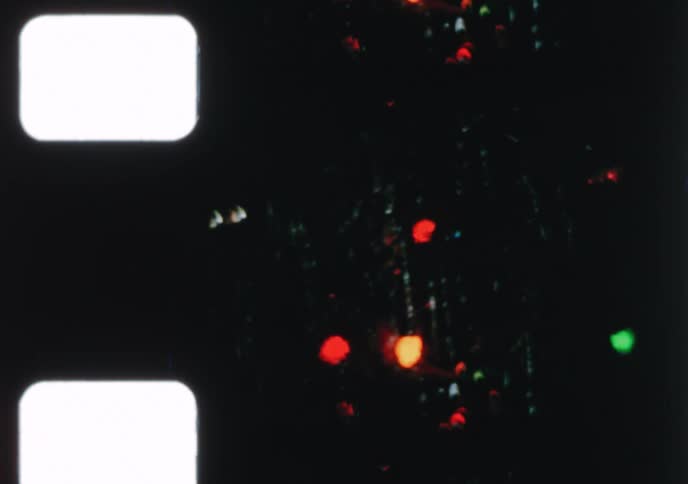 Authentic 8mm home movie from the 1970s shows a family happily decorating their Christmas tree with ornaments and lights