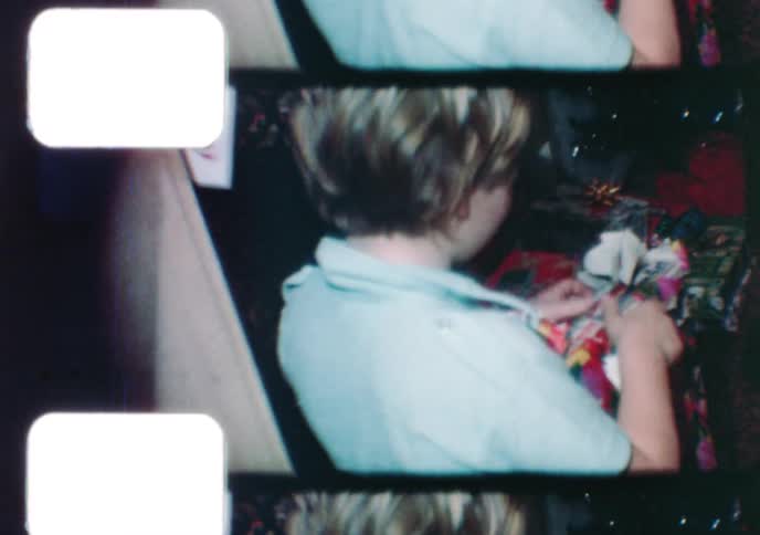 Vintage 1976 home movie shows a young boy smiling and unwrapping presents on Christmas morning