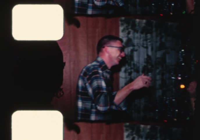 A young couple shares a romantic kiss and slow dance in front of a tinsel Christmas tree in this nostalgic home movie from the 1960s