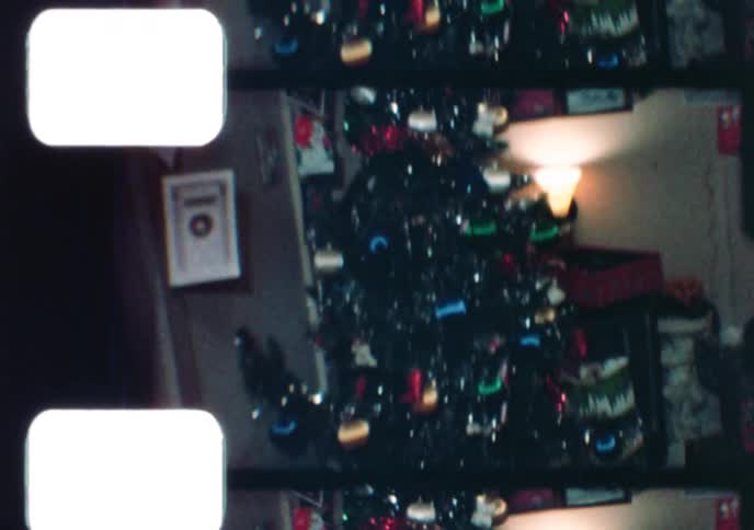 Vintage 8mm footage captures a heartwarming family Christmas gathering with children and grandparents in a cozy living room