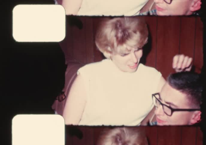 A young woman opens Christmas presents with her partner in this authentic 1960s home movie