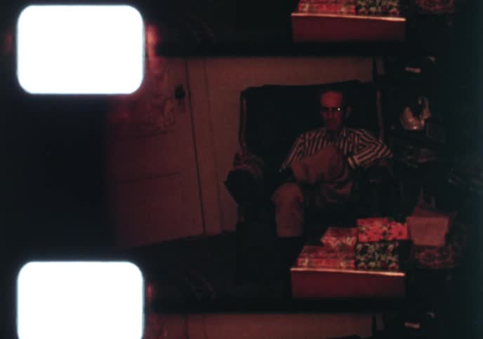 A nostalgic home movie from the 1960s captures a quiet Christmas scene with a decorated tree, gifts, and the messy aftermath of the celebration
