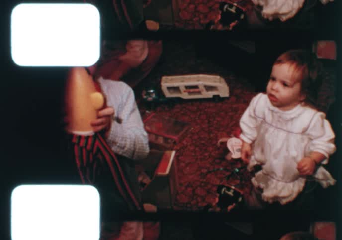 A young boy excitedly plays with his new Ernie puppet after opening Christmas presents with his family in this vintage 1970s home movie