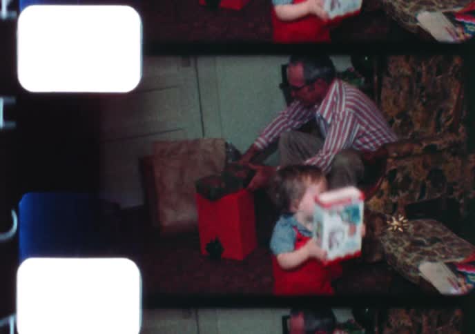 A compilation of vintage 8mm home movie footage captures a family celebrating Christmas morning and opening presents together