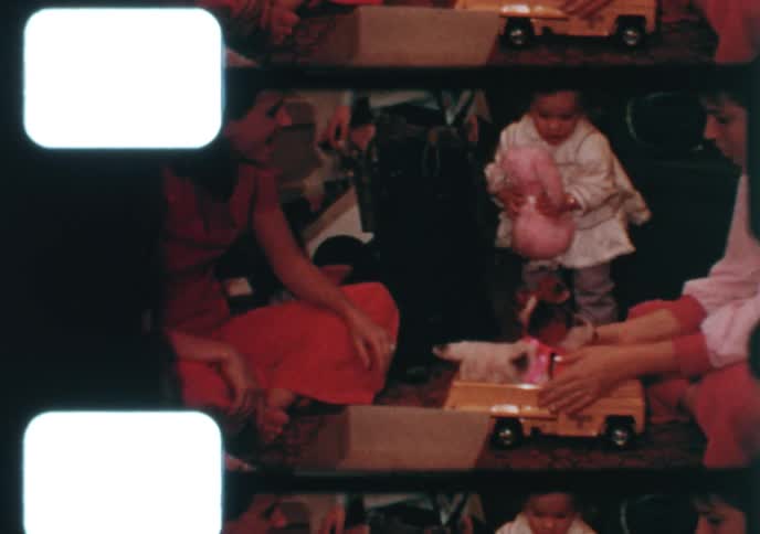 Vintage 8mm film captures the happy chaos of young children opening their presents on Christmas morning