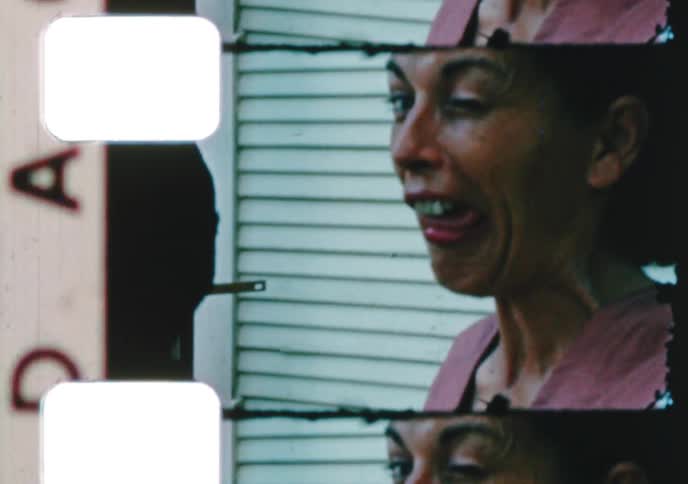 An archival home movie from the 1960s captures a playful woman making a silly face and drinking from a teacup