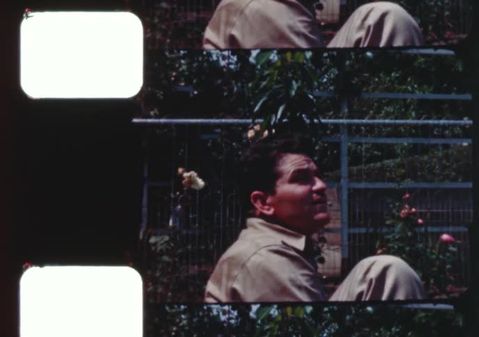 A vintage home movie captures a man and woman enjoying a game of croquet in their beautiful flower garden