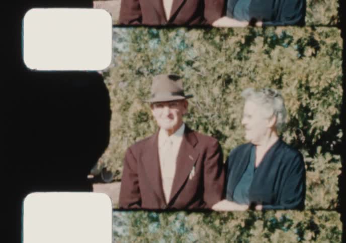 A vintage film scan captures an elderly couple smiling fondly for the camera outside