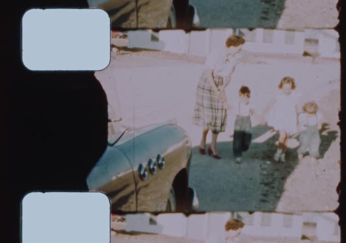A vintage 1950s film strip scan shows a mother and her three young children posing together outdoors by their classic car
