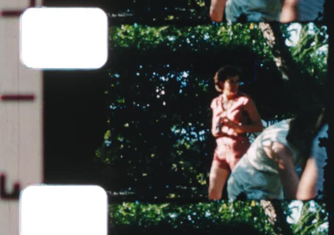 Candid archival footage from the 1950s shows a young woman smiling and another woman filming with a vintage camera