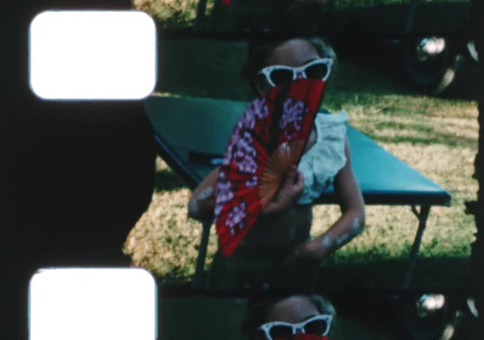 A man, woman, and child try on funny sunglasses and hats at a 1950s family party