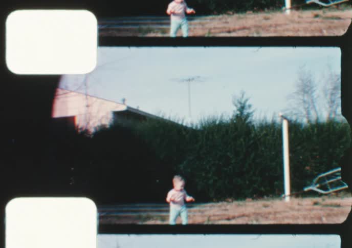 Adorable toddler boy smiles in the backyard while his father carries an antenna tower in this vintage 8mm home movie footage