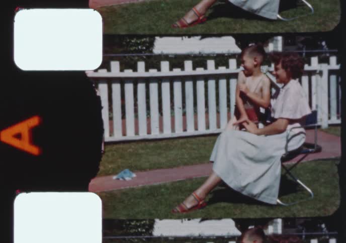 A vintage 1950s film scan shows a happy family and friends relaxing and posing together in a sunny suburban backyard