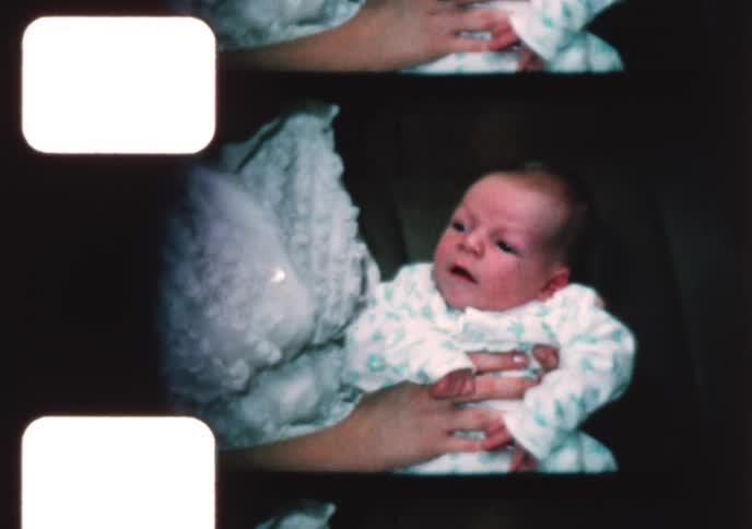 Vintage 8mm footage from the 1960s shows a young mother tenderly brushing her newborn baby's hair