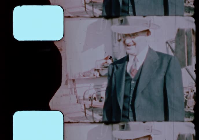 Vintage 1940s home movie shows a man in a suit being joined by a father holding his child for a family portrait