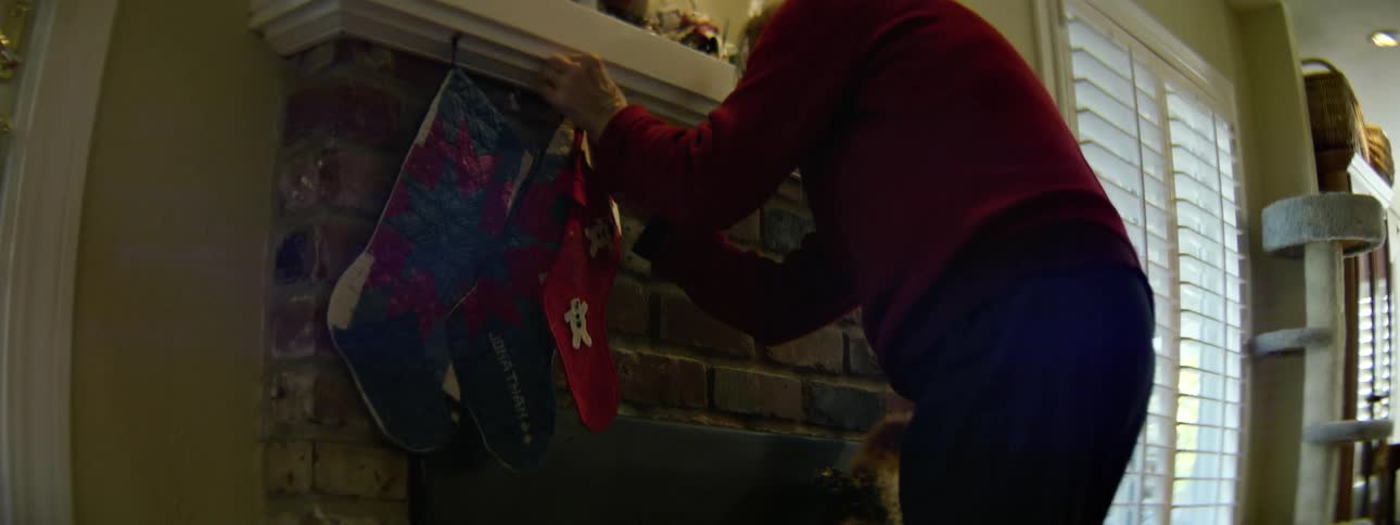 A woman hangs christmas stockings on a fireplace mantle