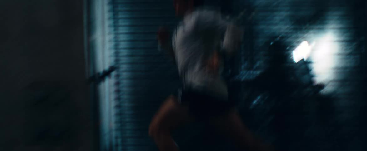 A determined male athlete runs at a fast pace through a dimly lit concrete tunnel or parking garage