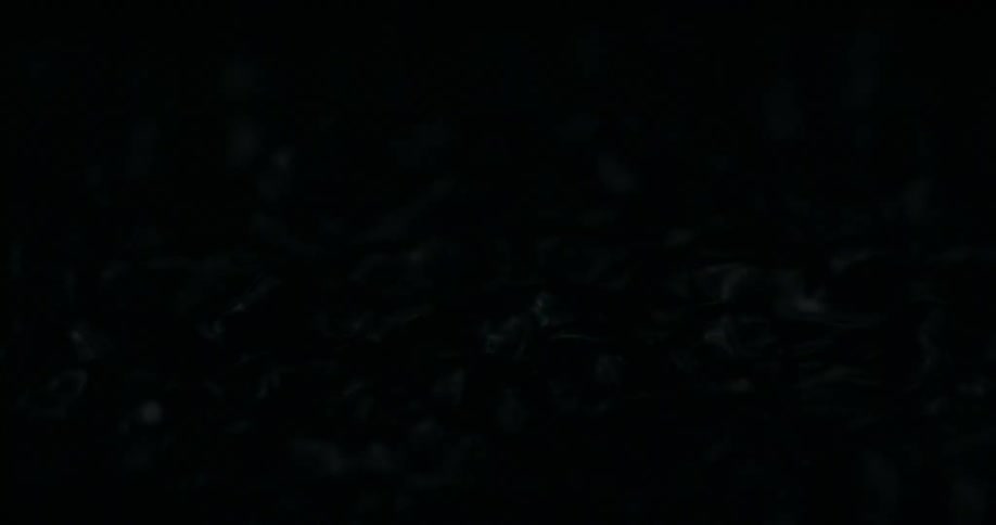 Raindrops fall into a dark, viscous liquid, creating mesmerizing ripples in extreme slow motion