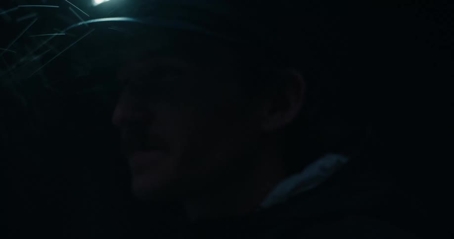 An intense close-up shot follows a determined adventurer with a headlamp as he navigates through a dark, snowy night