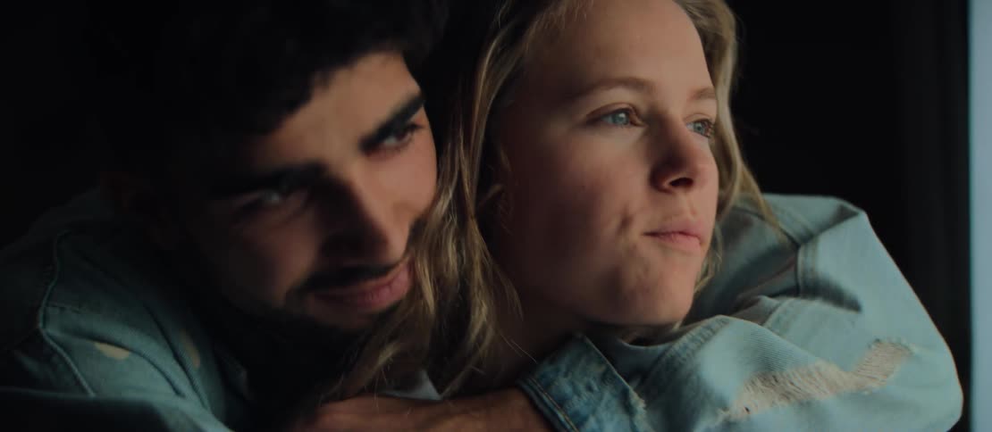 An affectionate young couple shares an intimate kiss and embrace during a quiet, romantic evening at home
