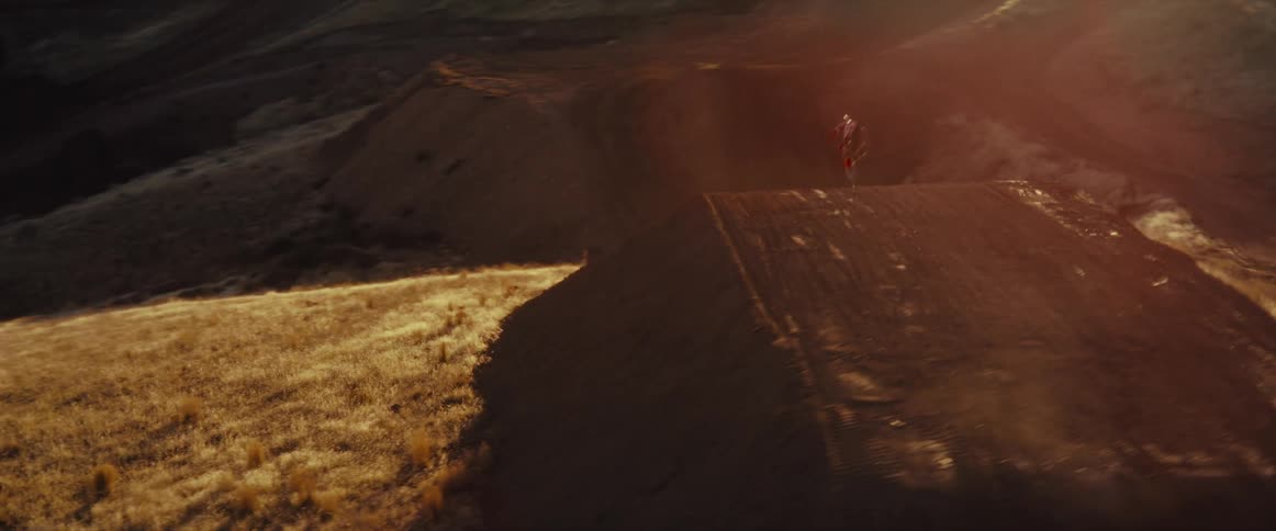 Stunning slow-motion aerial shot of a motocross rider performing a massive jump against the golden sunset