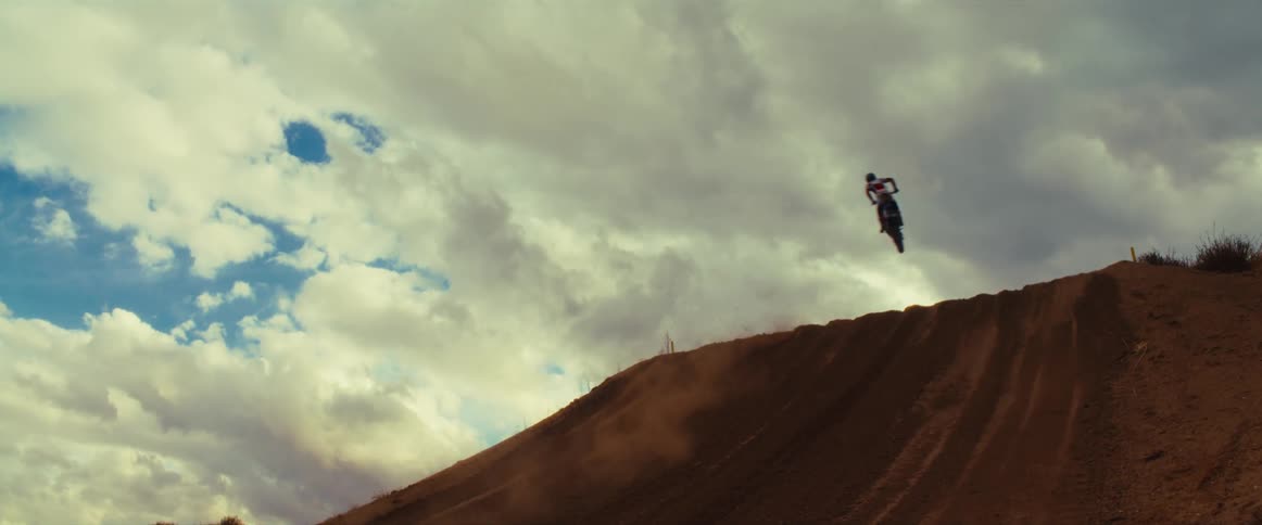 Epic slow motion video of a motocross rider flying through the air off a dirt hill