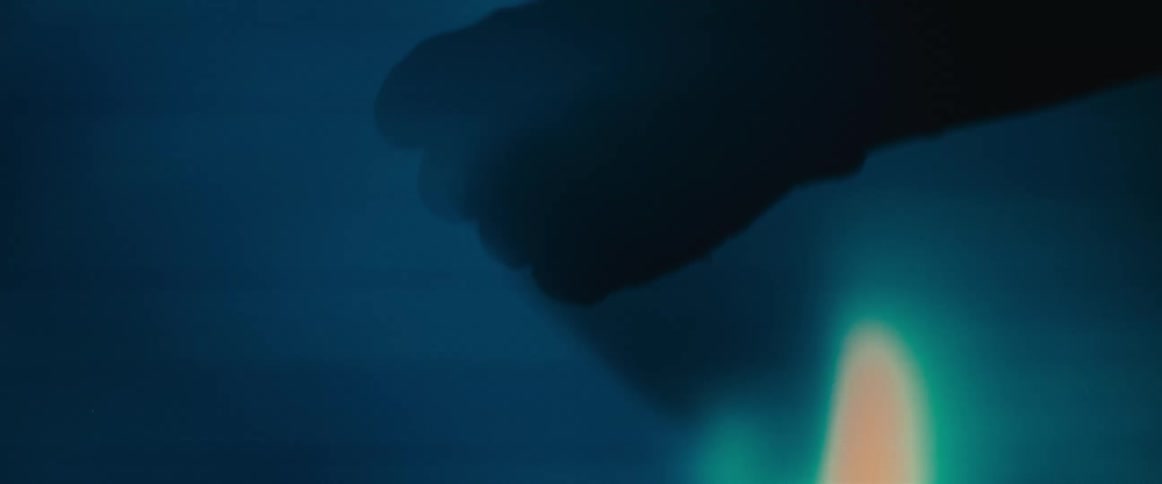 The eerie silhouette of a hand clenches into a fist and then opens against a moody blue background